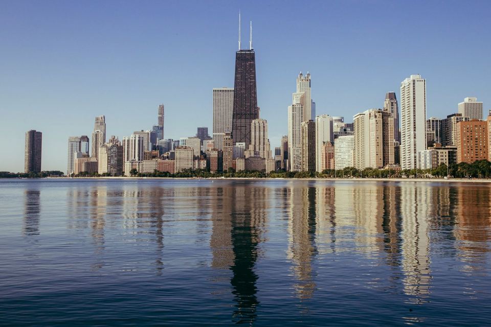Chicago's skyline reflected in a calm Lake Michigan, seen from the North Side lakefront